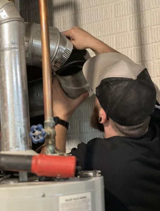 Technician repairing a residential gas line and flue connection