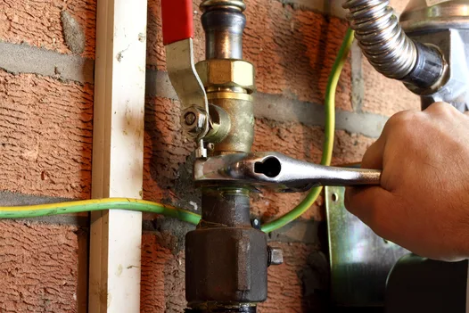 Technician tightening a residential gas pipe connection with a spanner