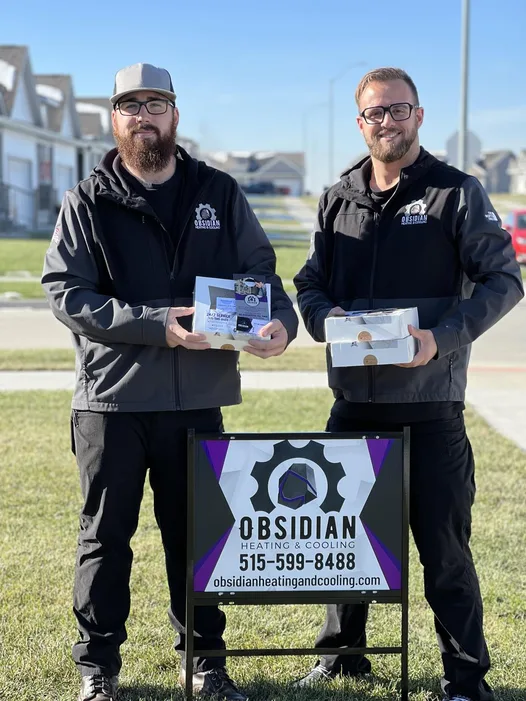 Obsidian Heating and Cooling owners at a customer&rsquo;s yard sign in Des Moines, IA